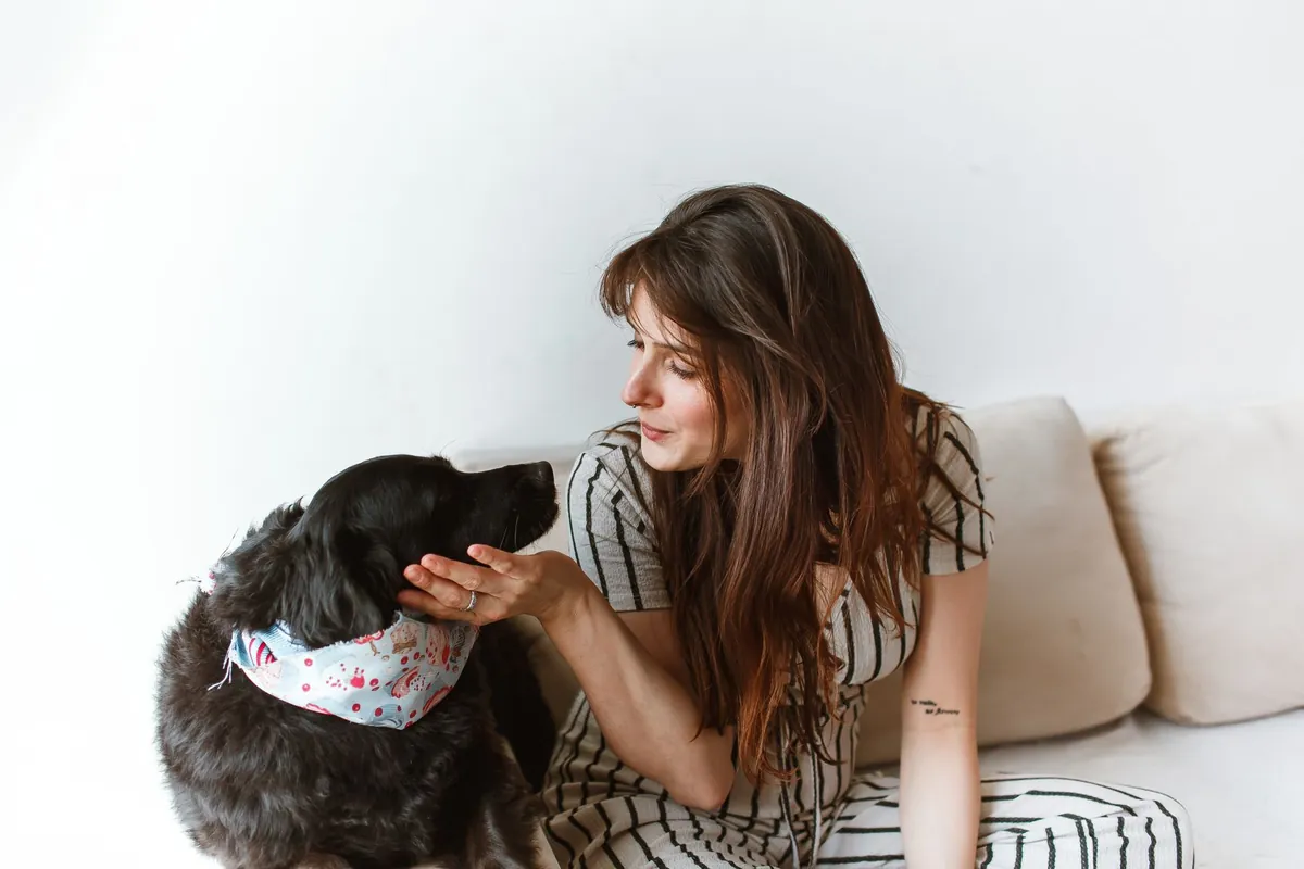Mujer sentada en el sofá observando con calma a su perro
